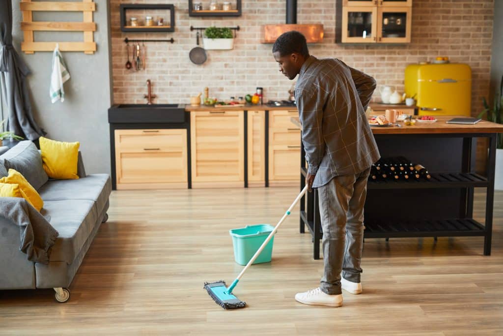 Jeune homme nettoyant les sols à la maison